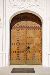 Large antique beautiful wooden door in a white building. St. Sophia Orthodox Cathedral in Polotsk on a sunny summer day, Belarus.