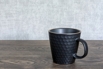 Ceramic tea cup on wooden table. Black dishes for hot drinks