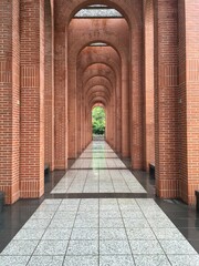 Endless red brick archway with trees reflection in a park after rain