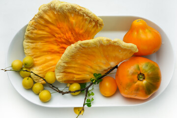 Lots of different yellow fruits and vegetables on a white plate. Wild forest chicken mushroom