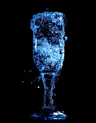 Splashes and drops of water in a glass are isolated on a black background.