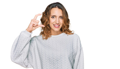 Beautiful young caucasian woman wearing casual winter sweater smiling and confident gesturing with hand doing small size sign with fingers looking and the camera. measure concept.