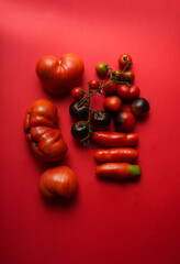 Red mixed form and color tomato on the red background 