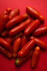 red slim tomatoes on red background 