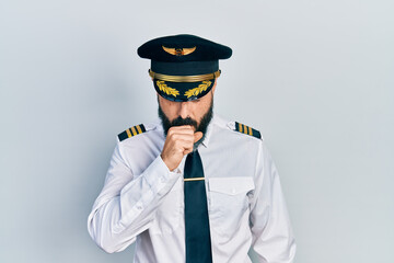 Young hispanic man wearing airplane pilot uniform feeling unwell and coughing as symptom for cold or bronchitis. health care concept. © Krakenimages.com