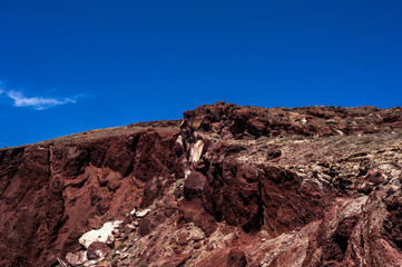 Fototapeta na wymiar Huge red rock cliff on red sand beach Santorini. Alien landscape.
