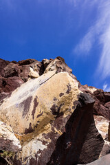 Obraz premium Huge red and yellow rock cliff on red sand beach Santorini. Alien landscape.