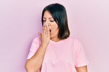 Young hispanic woman wearing casual pink t shirt bored yawning tired covering mouth with hand. restless and sleepiness.