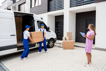 Two removal company workers unloading boxes from minibus into customer's home