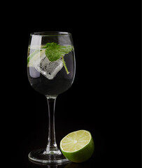a glass of fresh drinking water and lime. mineral water as a means to quench thirst. on a black...