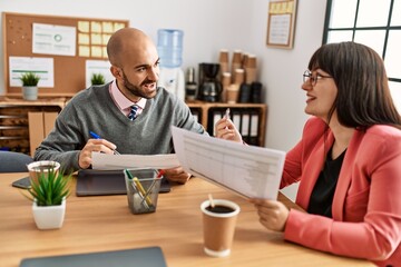 Two hispanic business workers smiling happy working at the office.
