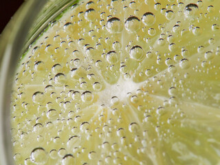 a glass of fresh drinking water and lime. mineral water as a means to quench thirst. on a black...