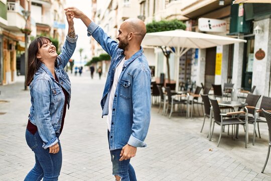 Young hispanic couple smiling happy dancing at the city.