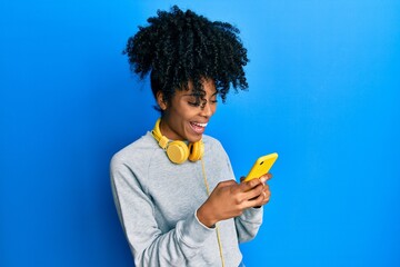 African american woman with afro hair using smartphone typing message smiling and laughing hard out...