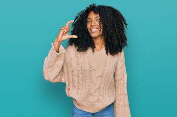 Young african american girl wearing casual clothes smiling and confident gesturing with hand doing small size sign with fingers looking and the camera. measure concept.