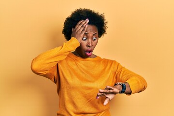 Young african american woman wearing casual clothes looking at the watch time worried, afraid of...