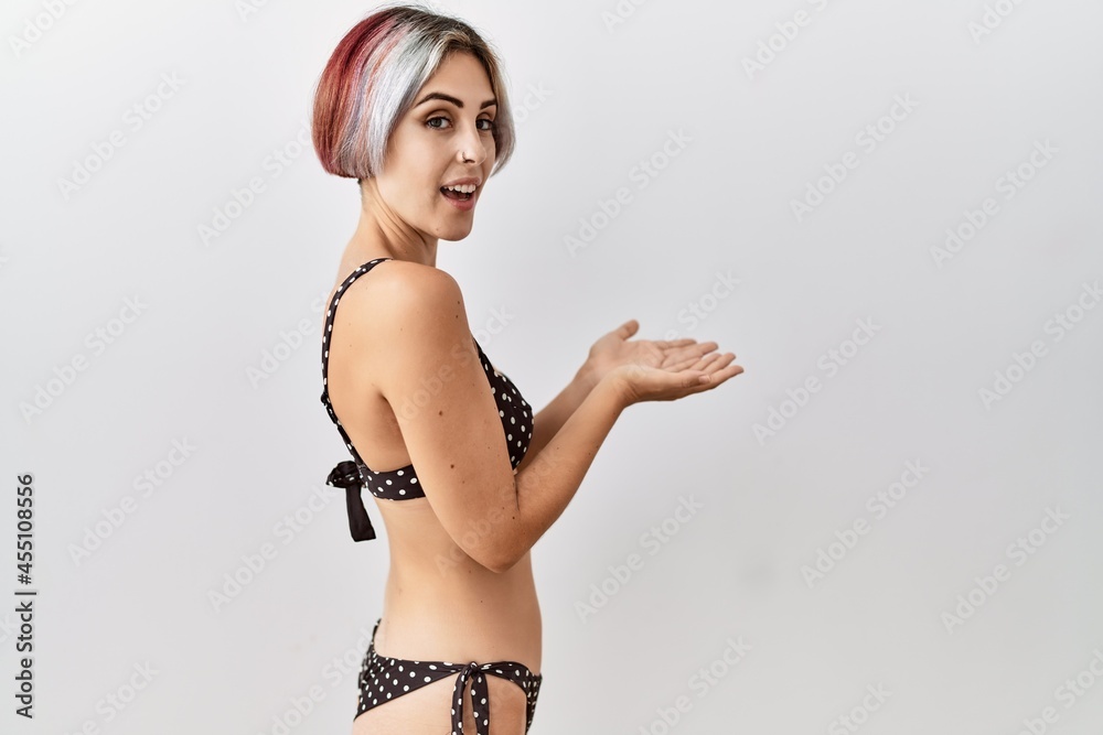 Sticker young beautiful woman wearing swimsuit over isolated background pointing aside with hands open palms