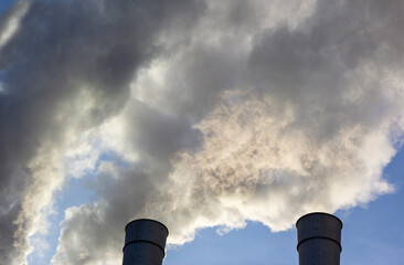 Air pollution by smoke coming out of two factory chimneys. Close-up from below of smoke coming out...