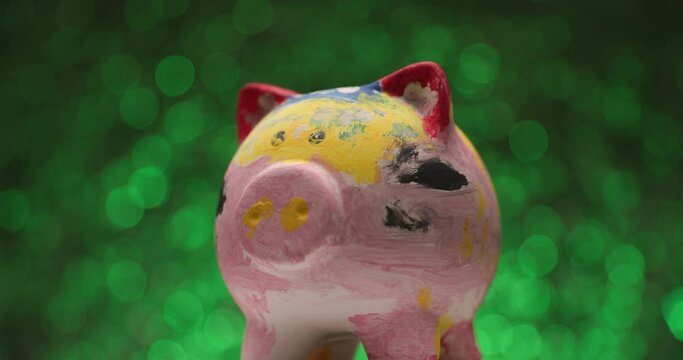 painted piggy bank spinning from one side to another on green background