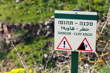 Warning sign on Rocky canyon edge. Text  Danger - Cliff Edge written in English, Hebrew and Arabic....