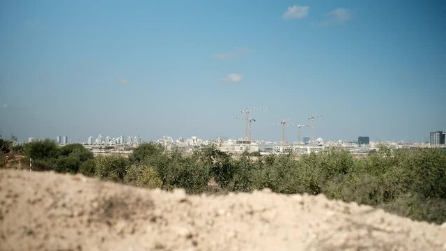 A focus change between a close sand pile, to a distance city and focus back to the dry sand. a 4K video clip, Rishon LeTsiyon sand dunes, Israel.