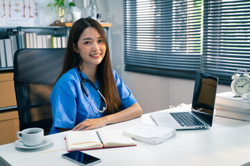 Portrait shot of female doctor while working on laptop in doctor’s office.