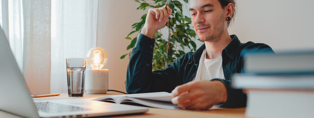 College student at campus while studying virtual learning for pass exam to university. Young man...