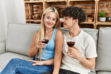 Young couple smiling happy toasting with red wine glass at home.
