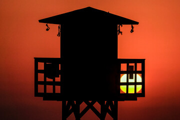 Fototapeta na wymiar panoramic view of a lifeguard hut on the beach with the sea in the background and the sun on the horizon