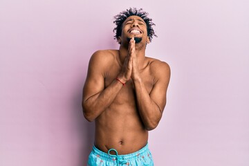 Young african american man with beard wearing swimsuit begging and praying with hands together with...