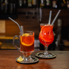 Autumn drinks like grog and hot ginger tea served in glasses with straws on wooden counter in cafe 