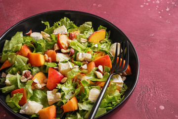 Salad with cheese and peach on a black plate