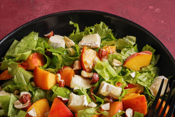 Salad with cheese and peach on a black plate