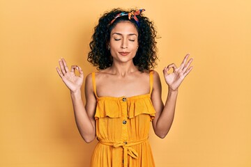 Young latin girl wearing summer dress relax and smiling with eyes closed doing meditation gesture with fingers. yoga concept.