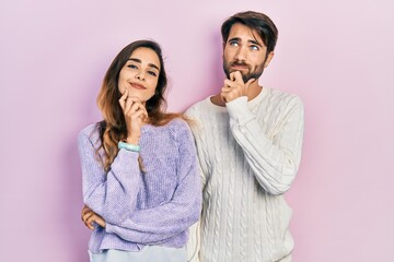 Naklejka premium Young hispanic couple wearing casual clothes looking confident at the camera smiling with crossed arms and hand raised on chin. thinking positive.