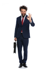 handsome businessman giving an ok sign and holding a briefcase