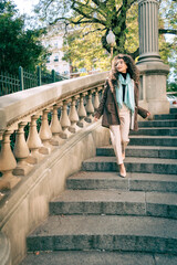 Beautiful curly-haired Hispanic woman walking down an old staircase from the early 20th century.