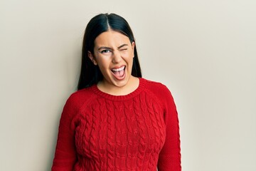 Fototapeta premium Beautiful brunette woman wearing wool winter sweater winking looking at the camera with sexy expression, cheerful and happy face.