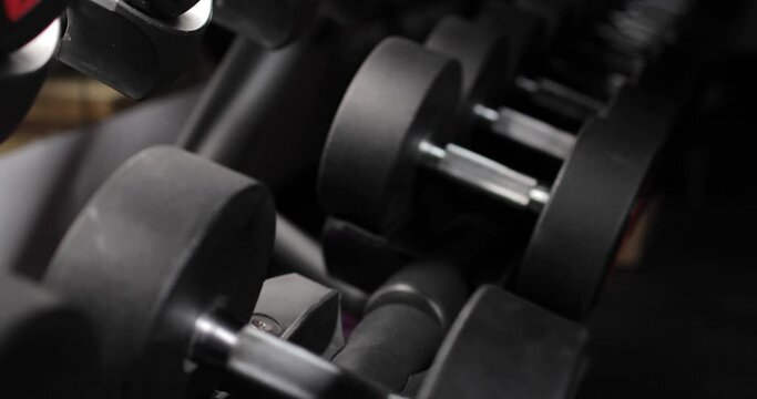 Male hand with smart watch taking a dumbbell in the gym. Close-up. Workout and bodybuilding fitness concept.