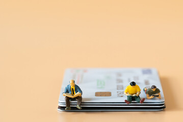 Miniature people figures Businessman sitting and reading Financial book or newspaper on credit card with copy space using as Success Business development and Blockchain Commerce Strategy Planning 