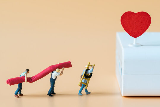 Miniature people Labor Worker walking carry ladder and red carpet for decorate stage with red heart using as special event making service business or Valentine day 14 February Lovely Happy Family idea - Powered by Adobe