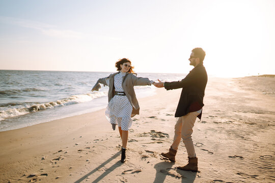 Young couple having fun walking and hugging on beach during autumn sunny day. Relaxation, youth, love,  lifestyle solitude with nature.