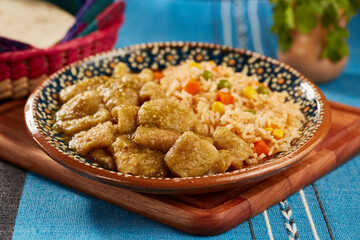 Chicharrón en salsa verde con arroz rojo mexicano servido en plato de barro