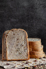 Sliced grain  whole wheat bread on dark rustic wooden background, bio ingredients, healthy food.