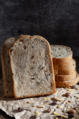 Sliced grain  whole wheat bread on dark rustic wooden background, bio ingredients, healthy food.