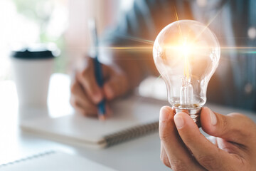 Innovation through ideas and inspiration ideas. Human hand holding light bulb to illuminate, idea...