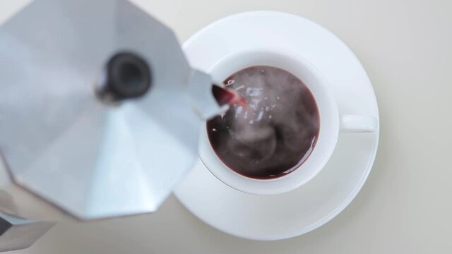 Cinemagraph, fresh brewed hot coffee pouring into white cup from geyser coffee maker, loop seamless motion, top view