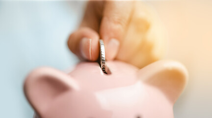 Woman inserts a coin into a piggy bank. Saving money for future plan and retirement fund concept.