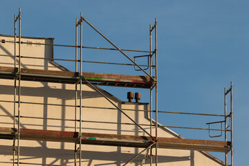Scaffolding standing next to a building against a blue sky background