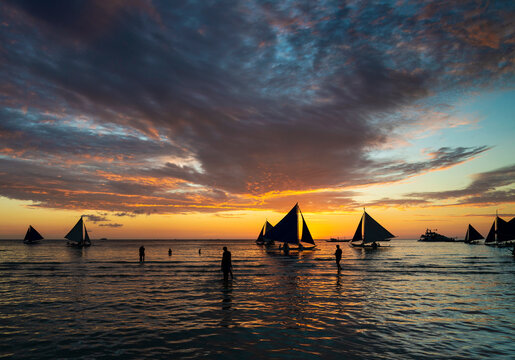 sunset with sailing boats and tourists in boracay island philippines